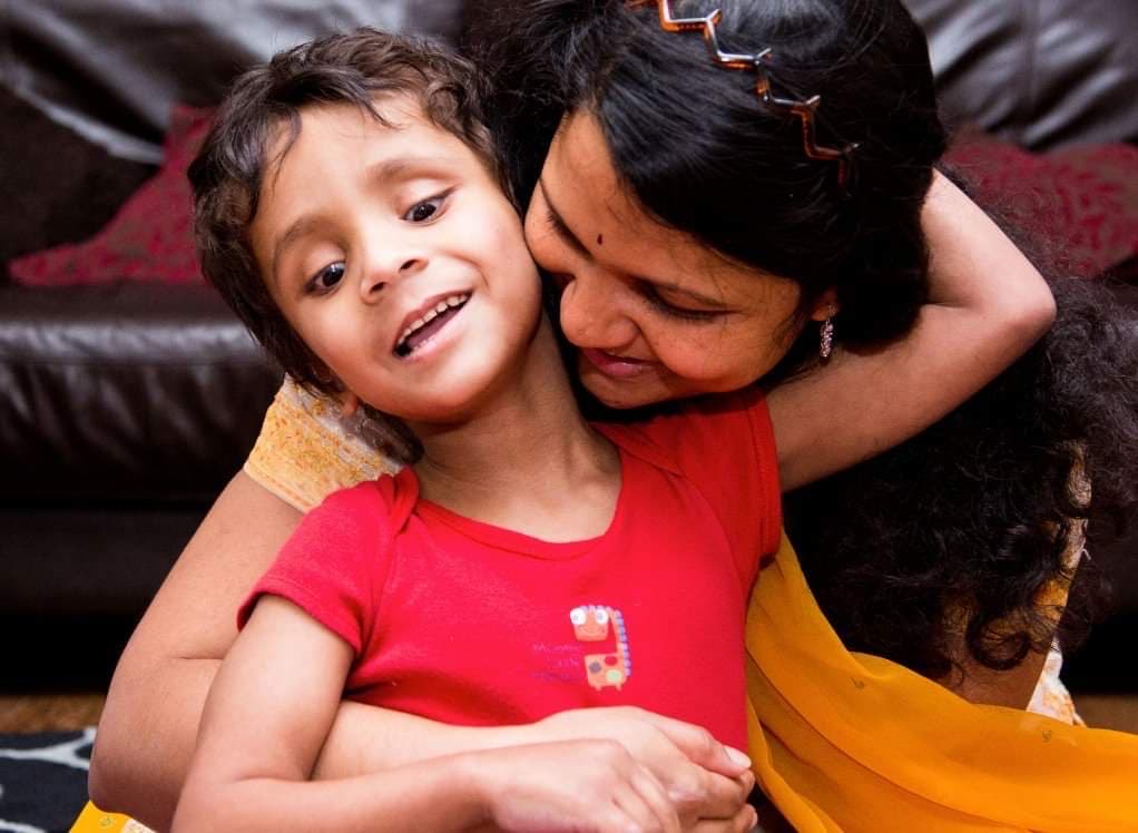 Child with disabilities and his mother cuddling, both smiling